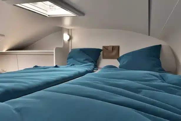 Innenansicht des Alkovenbetts im Wohnmobil A464 PRO mit blauer Bettwäsche und Dachfenster