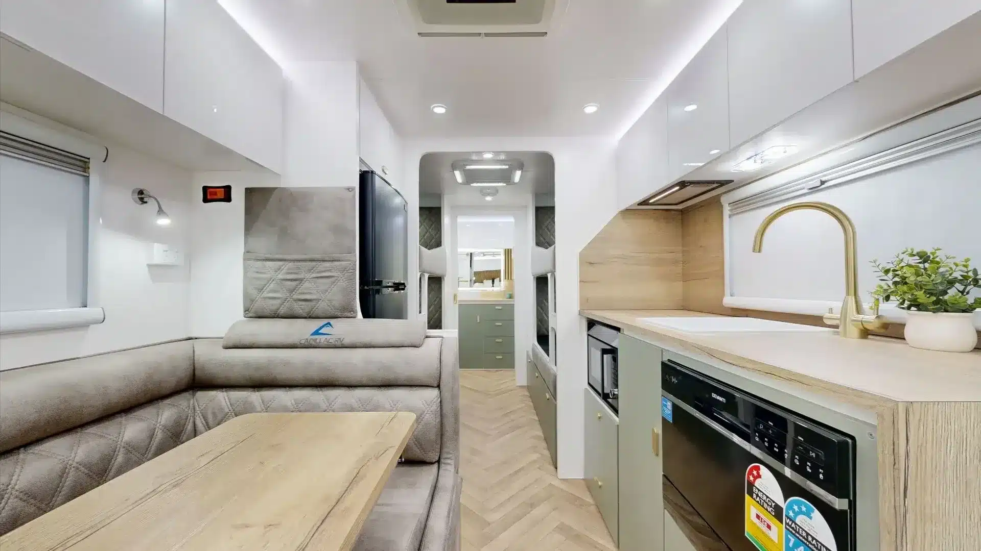 Innenansicht des Zeus Quad Bunk Caravan mit Sitzgruppe, Küche, Etagenbetten und modernen Einbauten