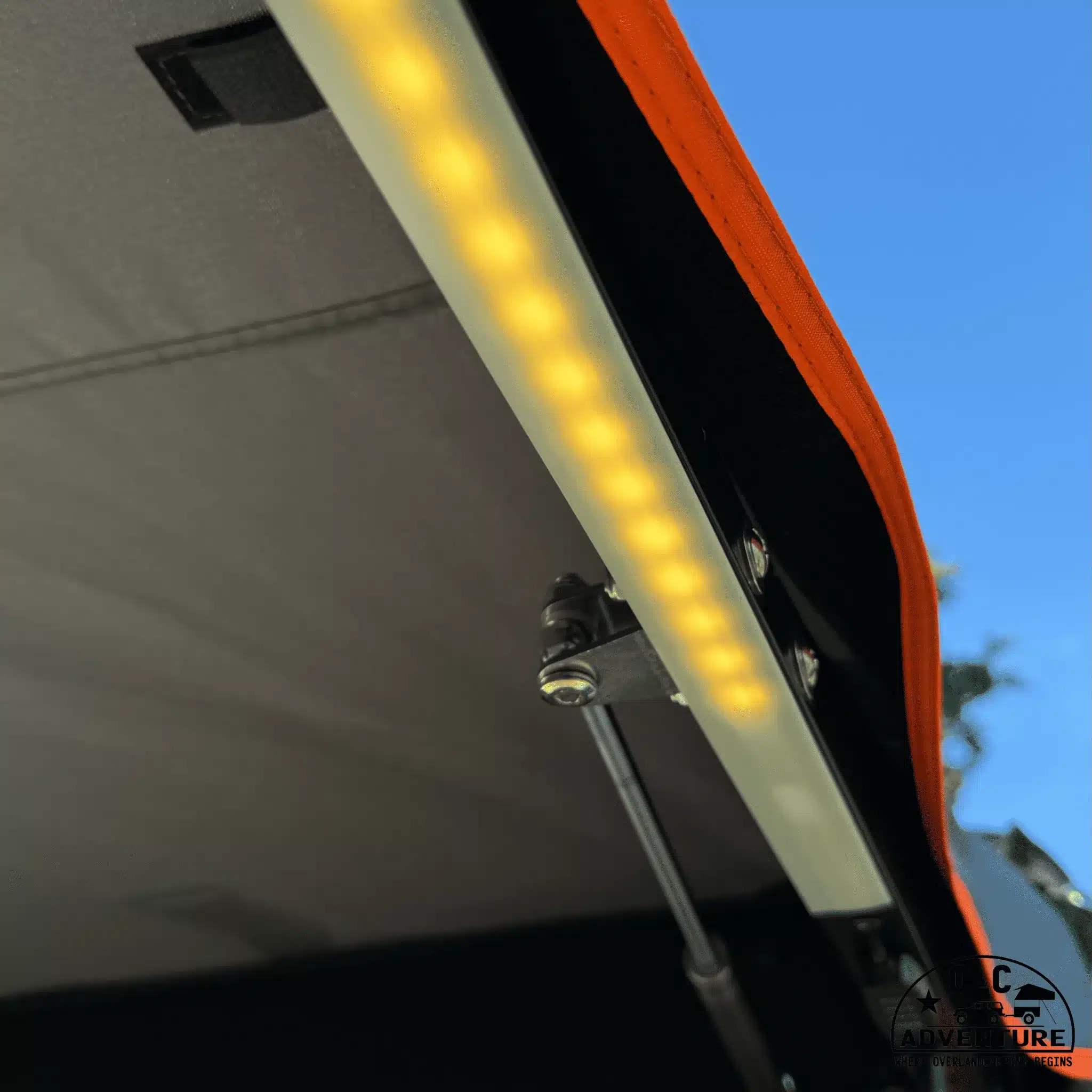 Nahaufnahme der integrierten LED-Leiste an einer freitragenden 180-Grad-Markise mit orangem Saum.