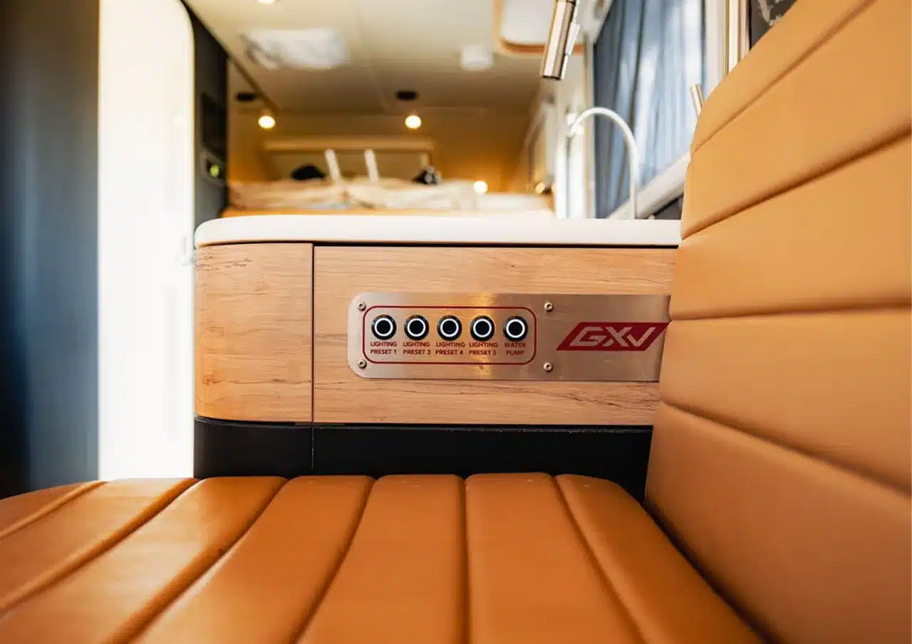 Innenansicht des GXV Hilt Expeditionsmobils mit Steuerpanel und Lederbank im Vordergrund.