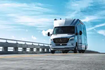 Airstream Atlas 2026, ein luxuriöser Reisemobil auf Mercedes-Benz Sprinter-Basis, fährt auf einer Brücke unter blauem Himmel