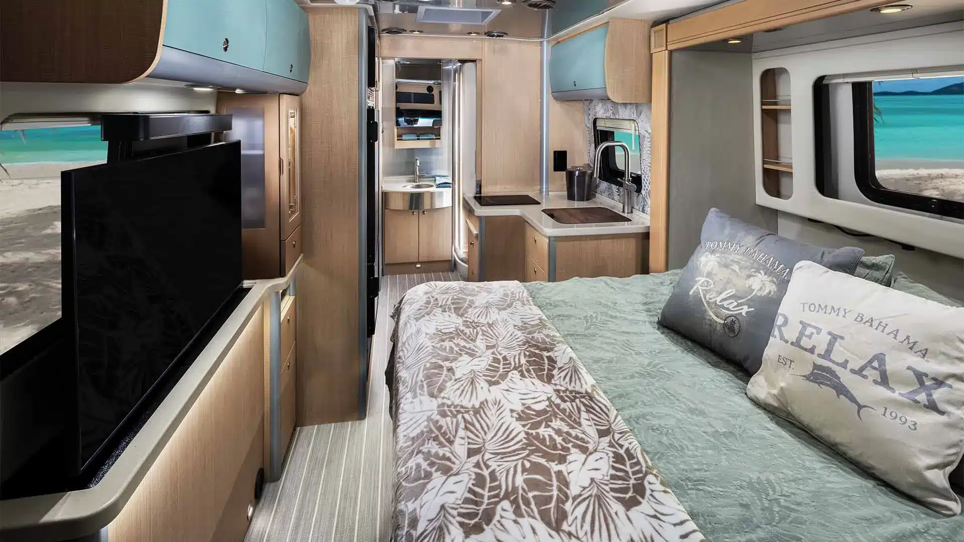 Wohn- und Schlafbereich des Airstream Atlas 2026 mit großem Bett, integrierter Smart-TV, Küche und geräumigem Bad im Hintergrund.