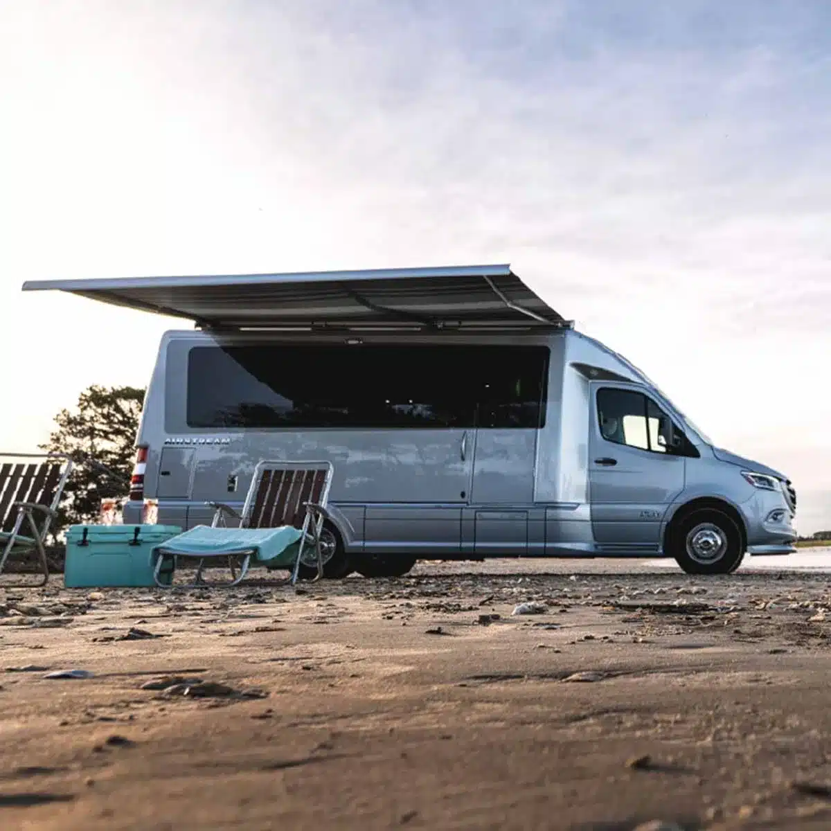 Airstream Atlas 2026 Reisemobil auf Mercedes-Sprinter-Basis mit Markise am Strand.