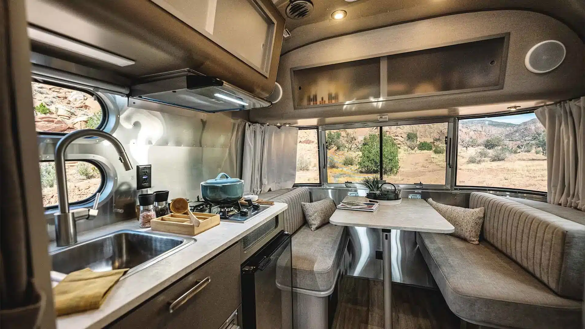 Innenraum des Airstream Caravel 16RB mit moderner Küche und wohnlicher Sitzgruppe am Fenster.