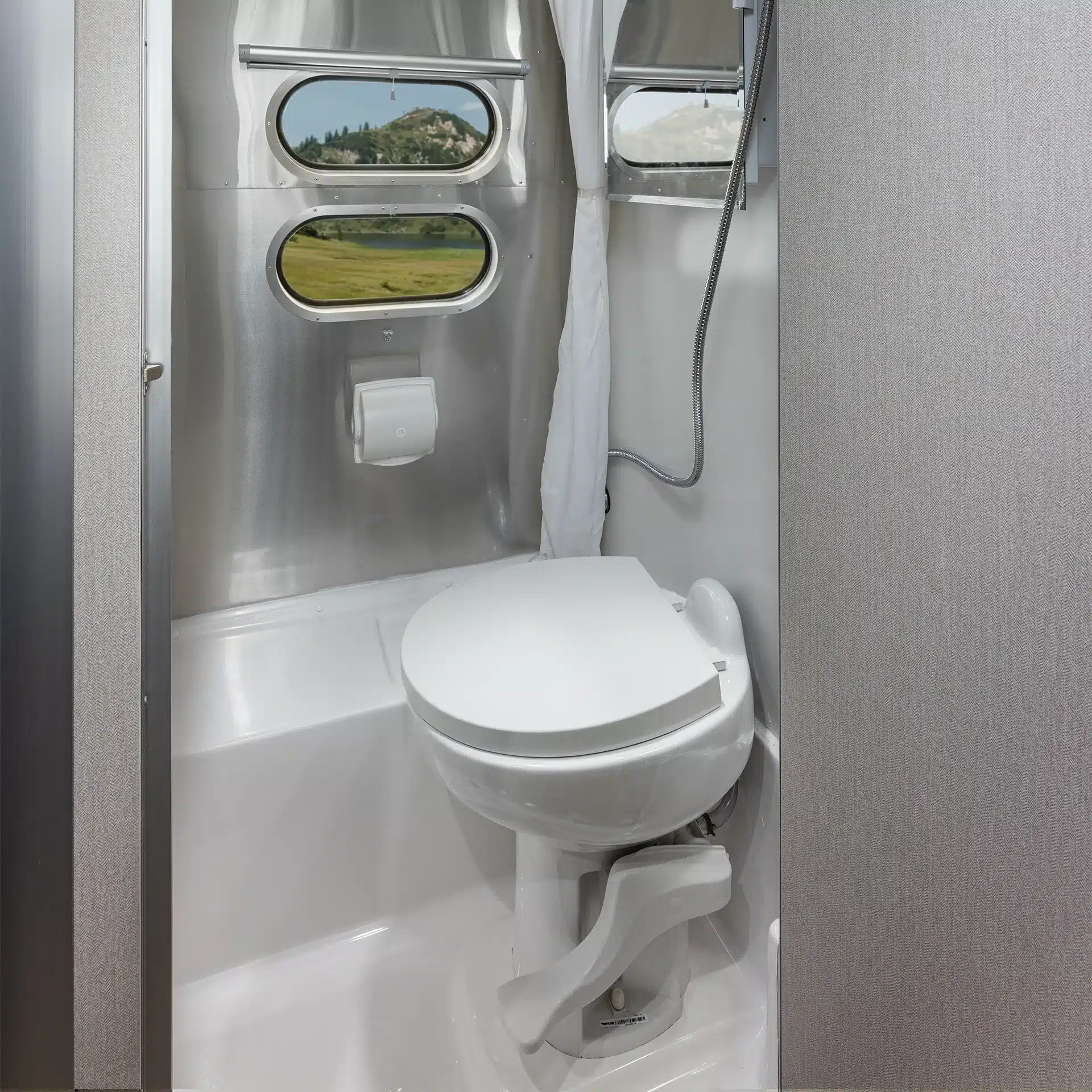 Nassbad mit Toilette, Fenster und Duschkopf im Airstream Caravel 16RB