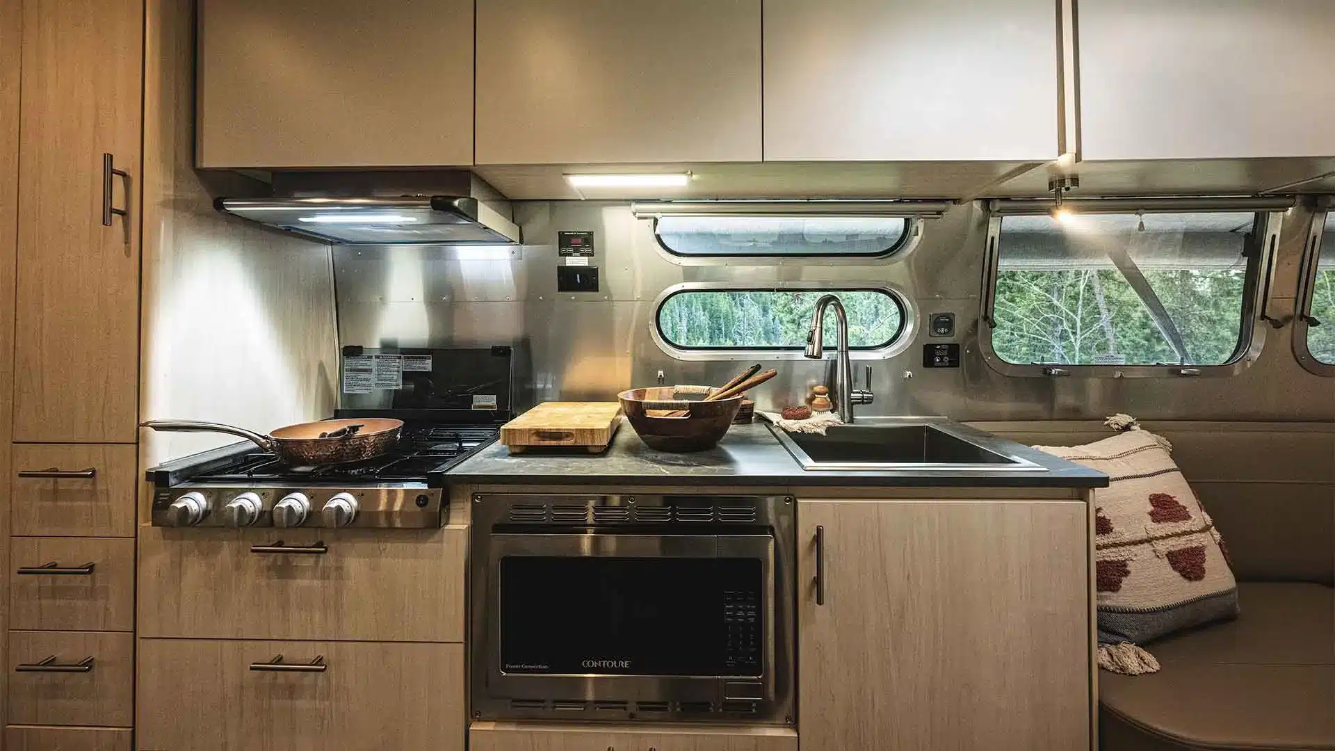 Moderne Küchenzeile mit Herd, Mikrowelle, Spüle und Stauraum im Airstream Flying Cloud 30FB Bunk