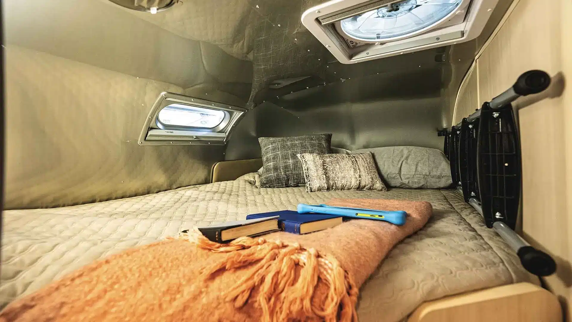 Schlafbereich mit Decke, Kissen und Bücherablage im Airstream Flying Cloud 30FB Bunk Travel Trailer.
