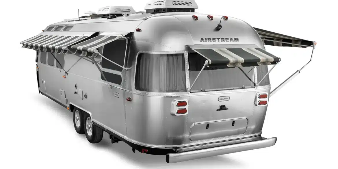 Airstream Globetrotter Wohnanhänger mit aufgeklappter Markise, sieht man von hinten seitlich.