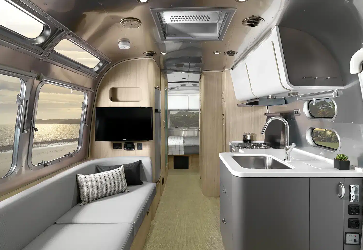 Innenansicht eines Airstream Globetrotter mit Küche, Sitzbereich und Blick ins Schlafzimmer