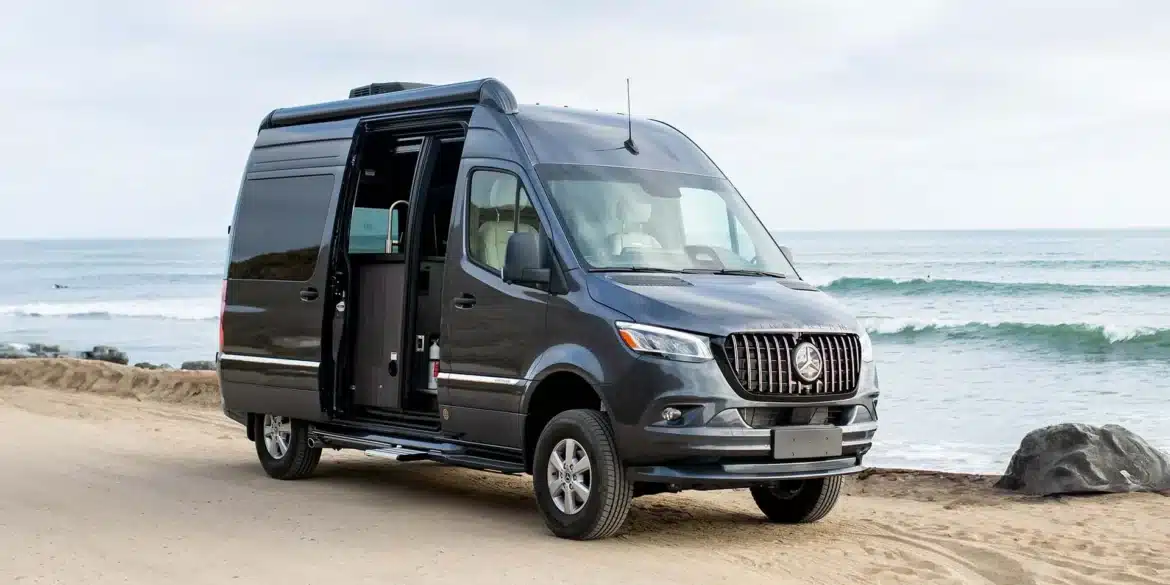 Airstream Interstate 19GT Kastenwagen am Strand mit geöffneten Türen, Meereskulisse im Hintergrund