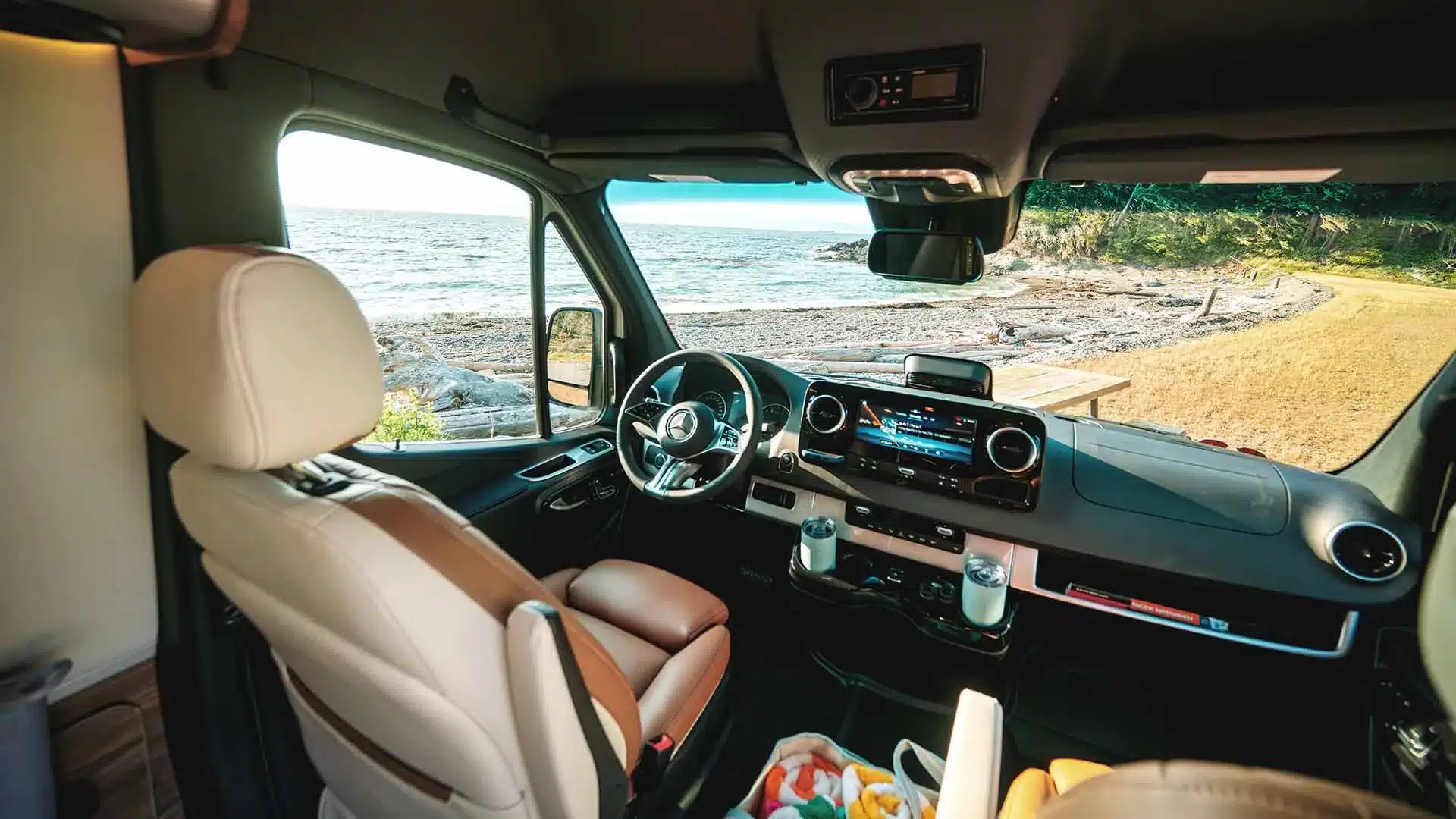 Innenansicht des Cockpits vom Airstream Interstate 24GL mit Ledersitzen und Meerblick durch die Frontscheibe.