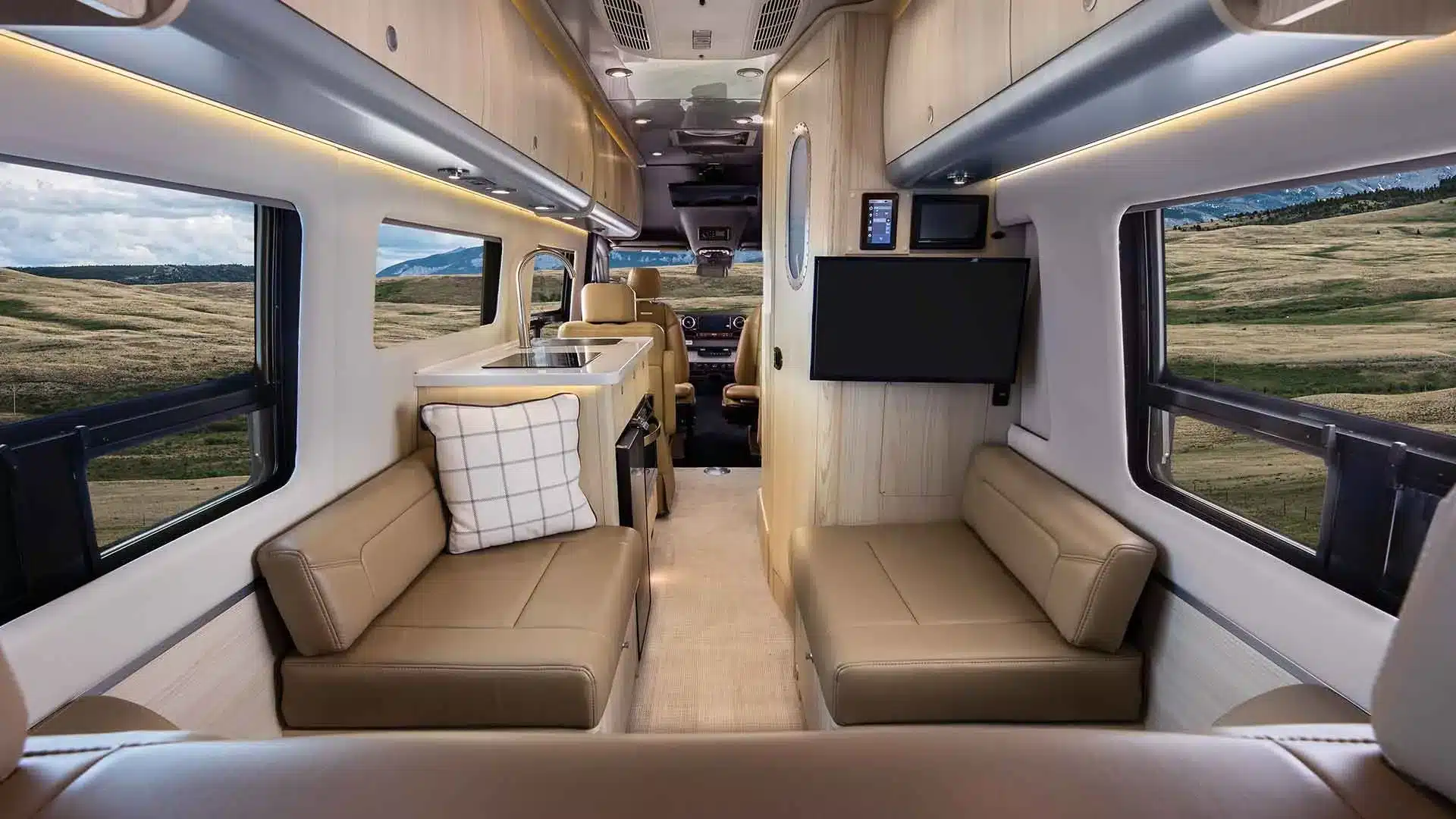Blick in den Innenraum des Airstream Interstate 24GL mit Ledersitzbänken, TV und moderner Küchenzeile