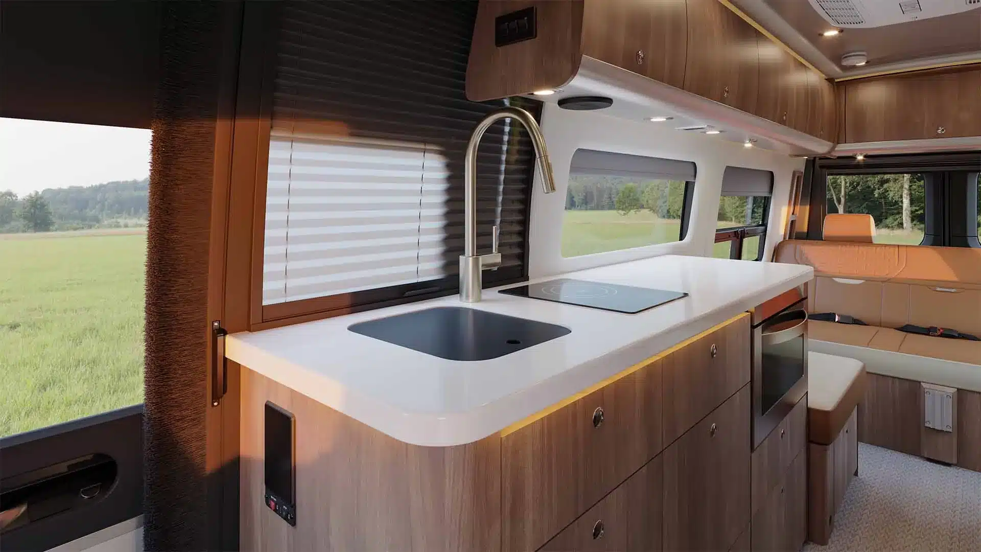 Innenansicht der Küche mit Spüle, Induktionskochfeld und Sitzgelegenheit im Airstream Interstate 24GTX Reisemobil.