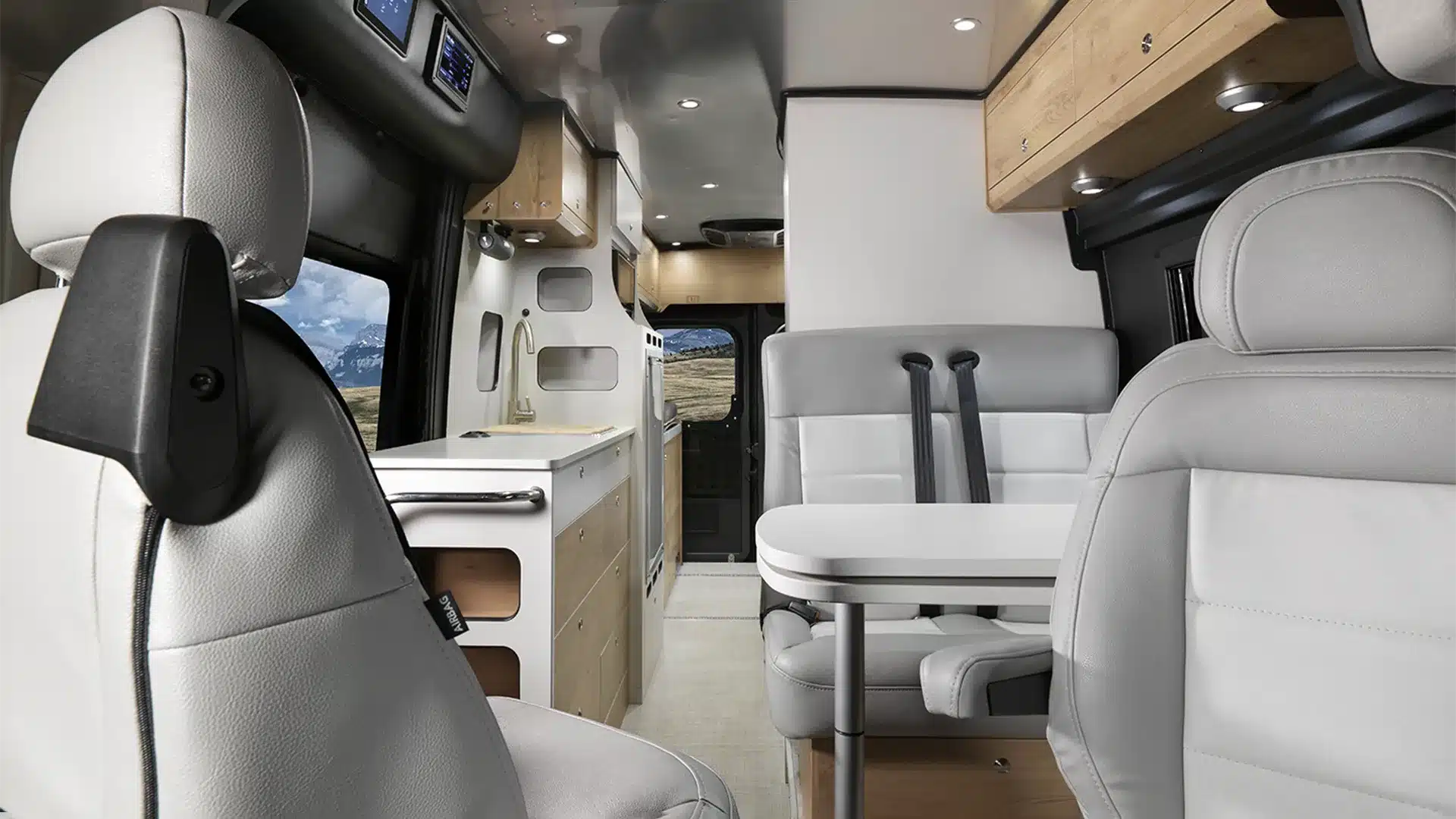Innenansicht des Airstream Rangeline 2026 Camper-Vans mit Sitzgruppe, Küche und Oberschränken.