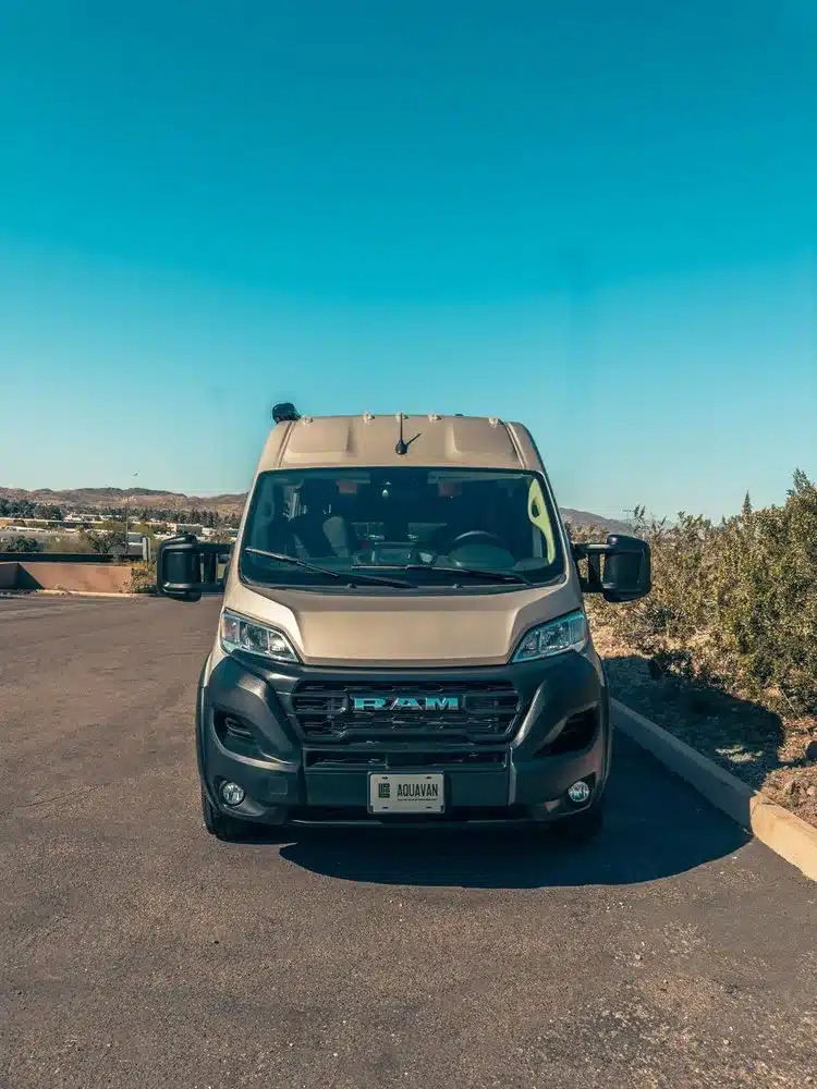 Frontansicht eines AQUAVAN Campervans auf Basis des RAM Promaster 2500 High Roof 159 Zoll, fotografiert auf einem Parkplatz bei klarer Witterung