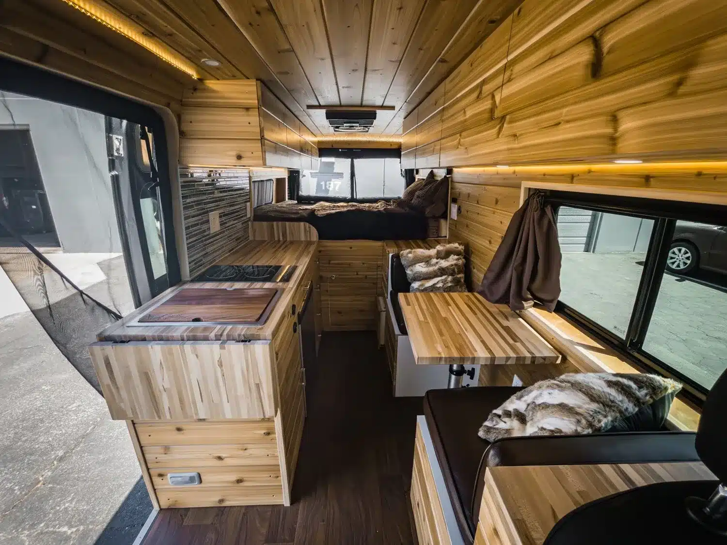 Innenraumansicht des Boho Jean Campervans: Küche, Sitzecke und Schlafbereich in einem Kastenwagen.
