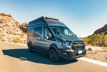 Ford Transit Trail als Boho Trinity Campervan mit Dachträger und Markise auf einer sonnigen Straße
