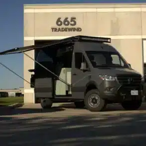 Campervan Bruce Peninsula von Vancini Conversions auf Mercedes-Basis mit ausgefahrener Markise vor Gebäude