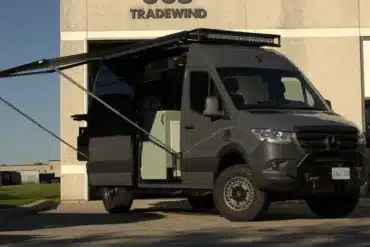 Campervan Bruce Peninsula von Vancini Conversions auf Mercedes-Basis mit ausgefahrener Markise vor Gebäude