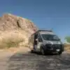 Butterfly RAM Promaster EXT Camper Van geparkt vor einer felsigen Bergkulisse unter blauem Himmel.
