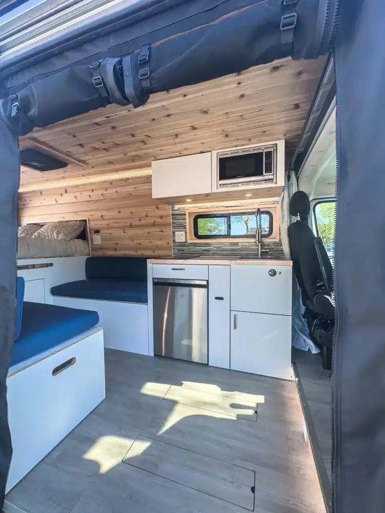 Innenraum des Butterfly RAM Promaster EXT mit Küchenzeile, Sitzbereich und Holzverkleidung