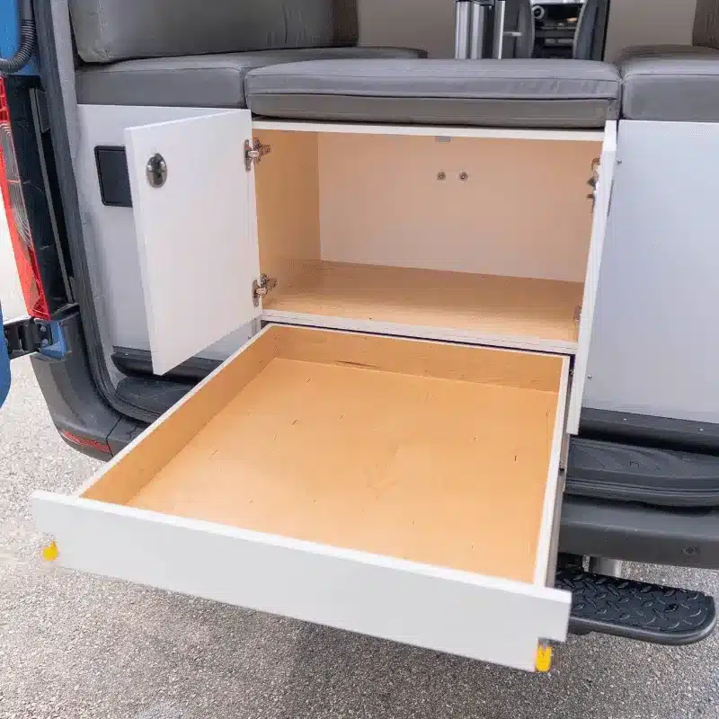 Geöffneter Stauschrank mit Schublade im Ausbau des Cape Breton Campervan, ausgelegt für flexibles Vanlife