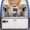 Innenansicht eines Cape Breton Campervans mit Sitzbänken, Tisch, Holzverkleidung und Stauraum
