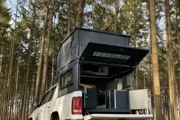 Capra Camper 3.0 Wohnkabine montiert auf Pick-up, aufgeklappt im Wald, Heckklappe geöffnet, Ausstattung sichtbar