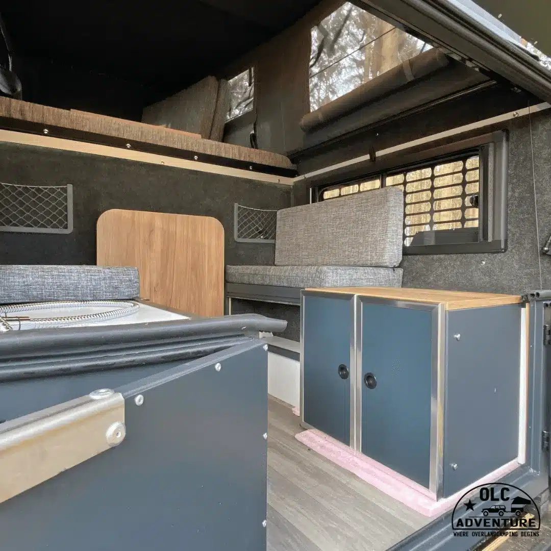 Innenraum der Capra Camper 3.0 absetzbaren Wohnkabine für Doppelkabiner-Pick-ups mit Polstern, Bett und Stauraum.