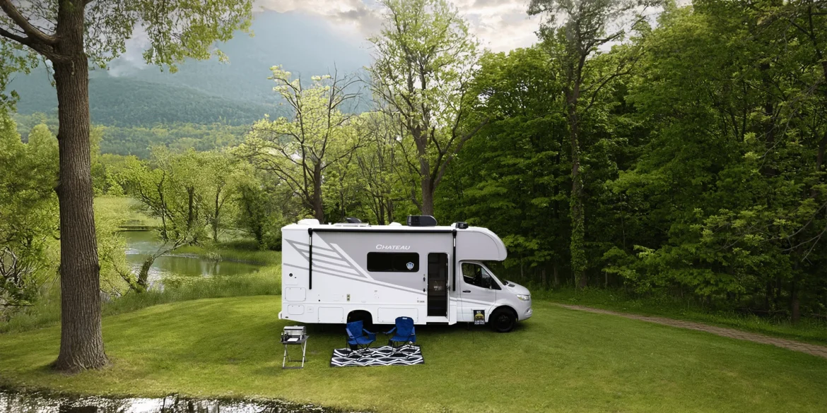 Chateau Sprinter 24LT Wohnmobil auf Sprinter-Basis, geparkt auf einer Wiese am Waldrand, mit Campingstühlen vor dem Fahrzeug.