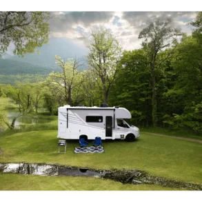 Chateau Sprinter 24LT Wohnmobil auf Sprinter-Basis, geparkt auf einer Wiese am Waldrand, mit Campingstühlen vor dem Fahrzeug.