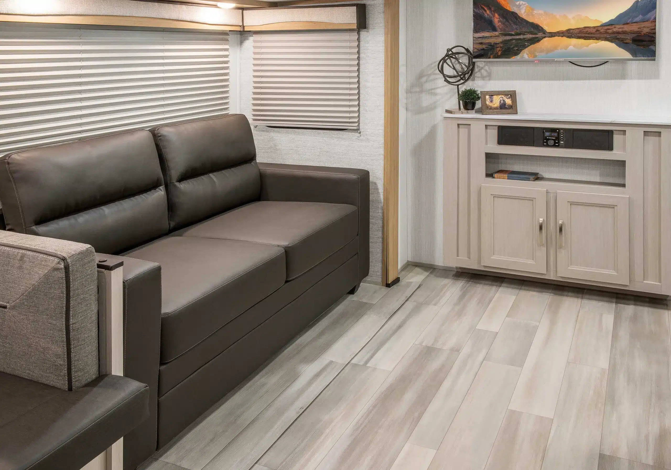 Wohnbereich im Cruiser Embrace EL26RB mit Ledersofa und Mediacenter aus hellem Holz.