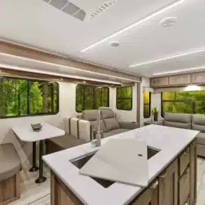 Moderner, heller Innenraum des Cruiser MPG 3010RL Travel Trailer mit Sitzgruppe, Sofa und Küchenzeile.