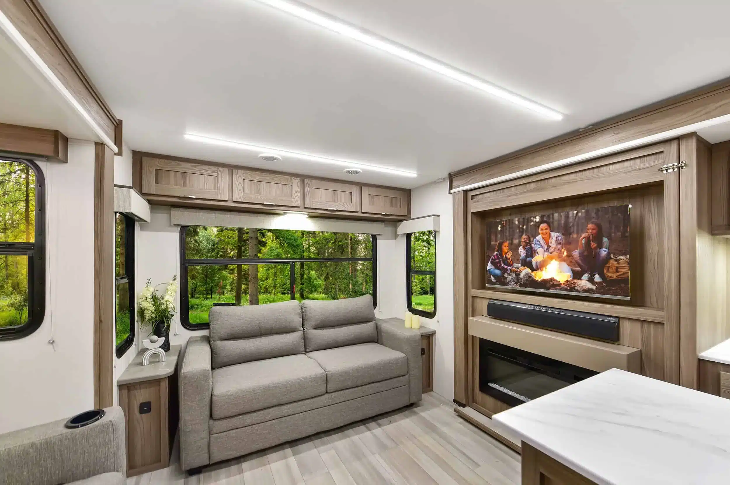 Innenraum des Cruiser MPG 3010RL Travel Trailer mit Sofa, großen Fenstern und Fernseher.