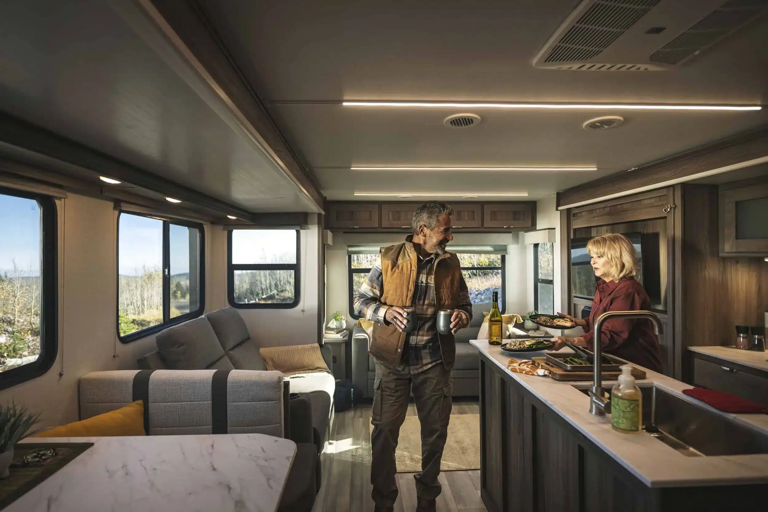 Modern eingerichteter Wohnbereich im Cruiser MPG 3010RL Travel Trailer mit zwei Personen in der Küche.