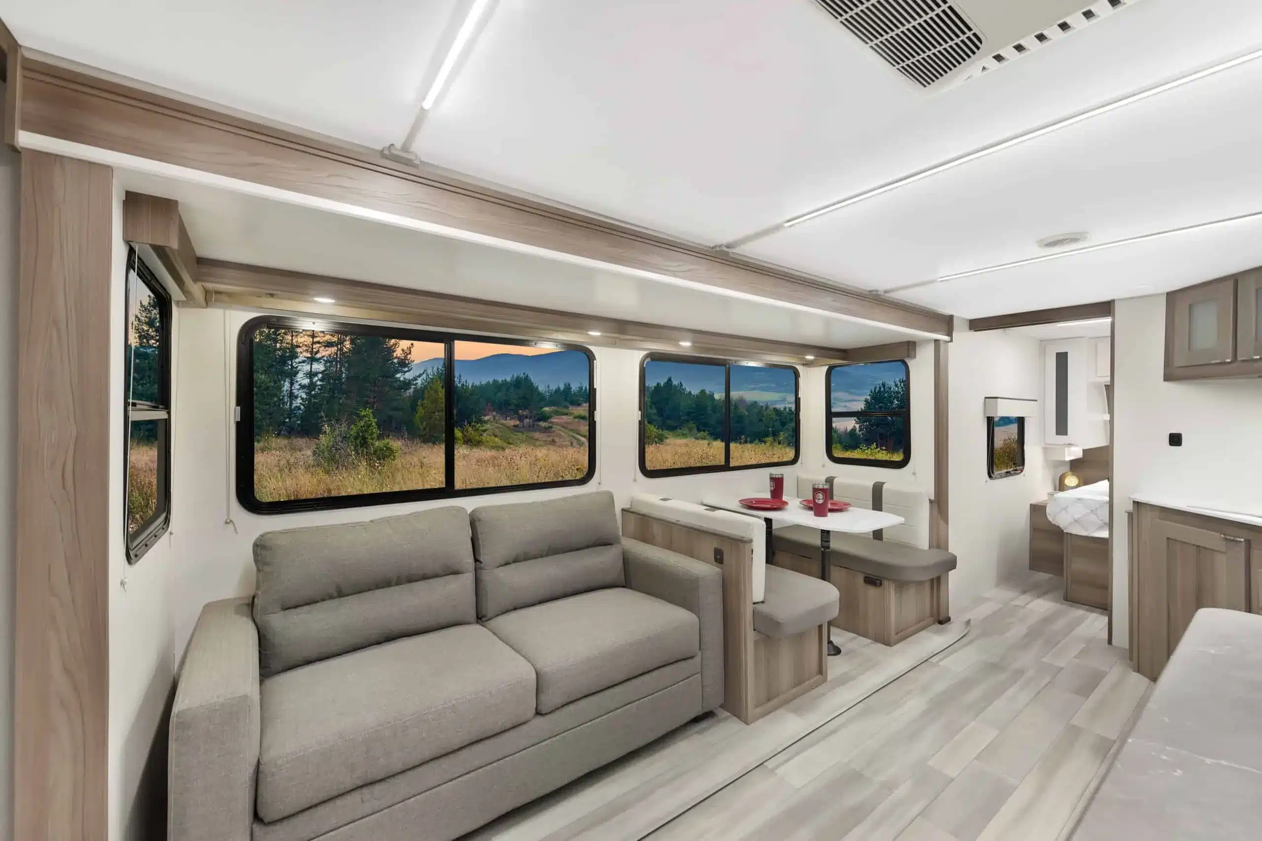 Modernes, helles Interieur eines Cruiser RV MPG 2650RB Travel Trailer mit Sofa, Essgruppe und großem Fenster.