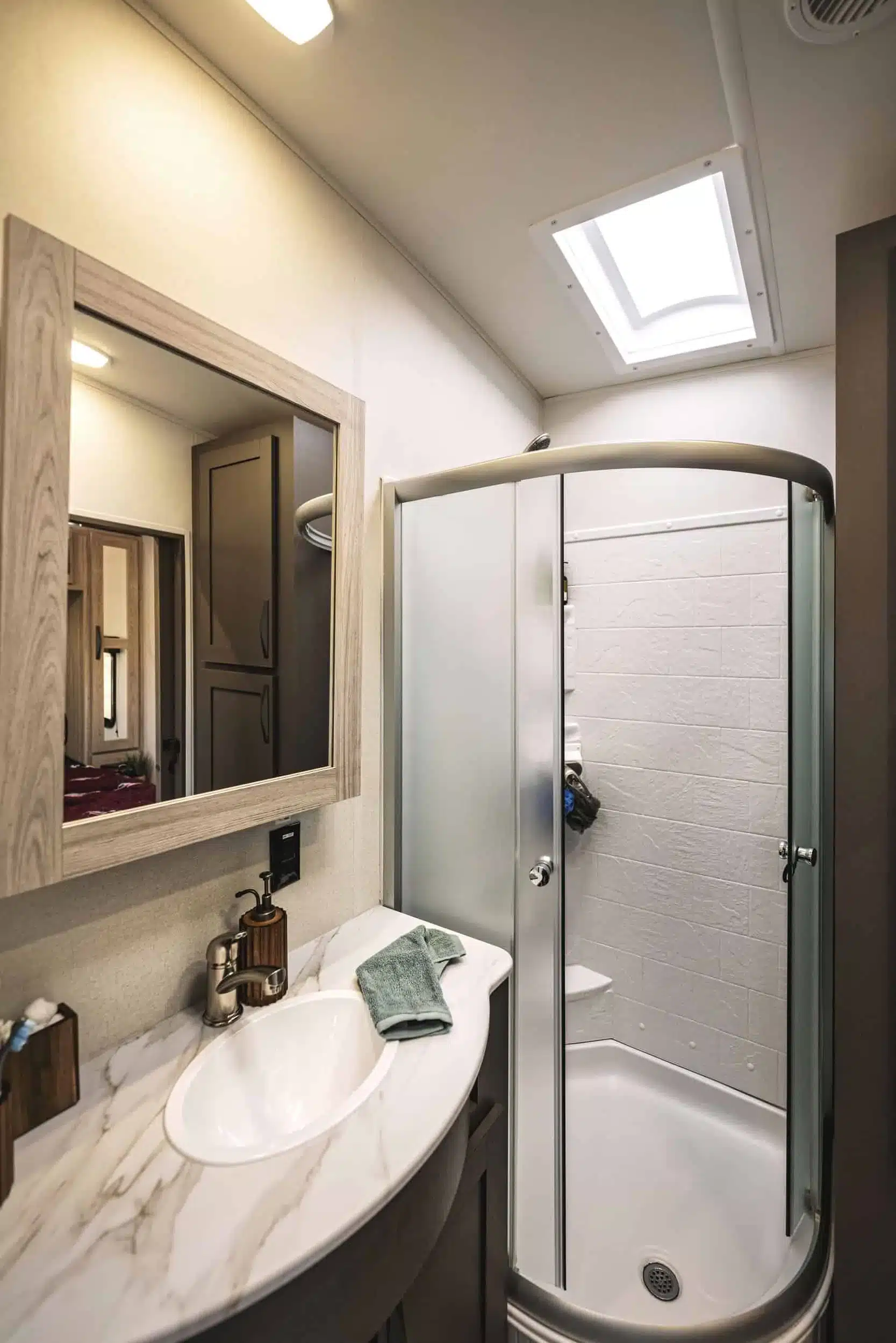 Badezimmer mit Spiegel, Waschbecken und runder Duschkabine im Wohnwagen Cruiser RV Stryker 3018