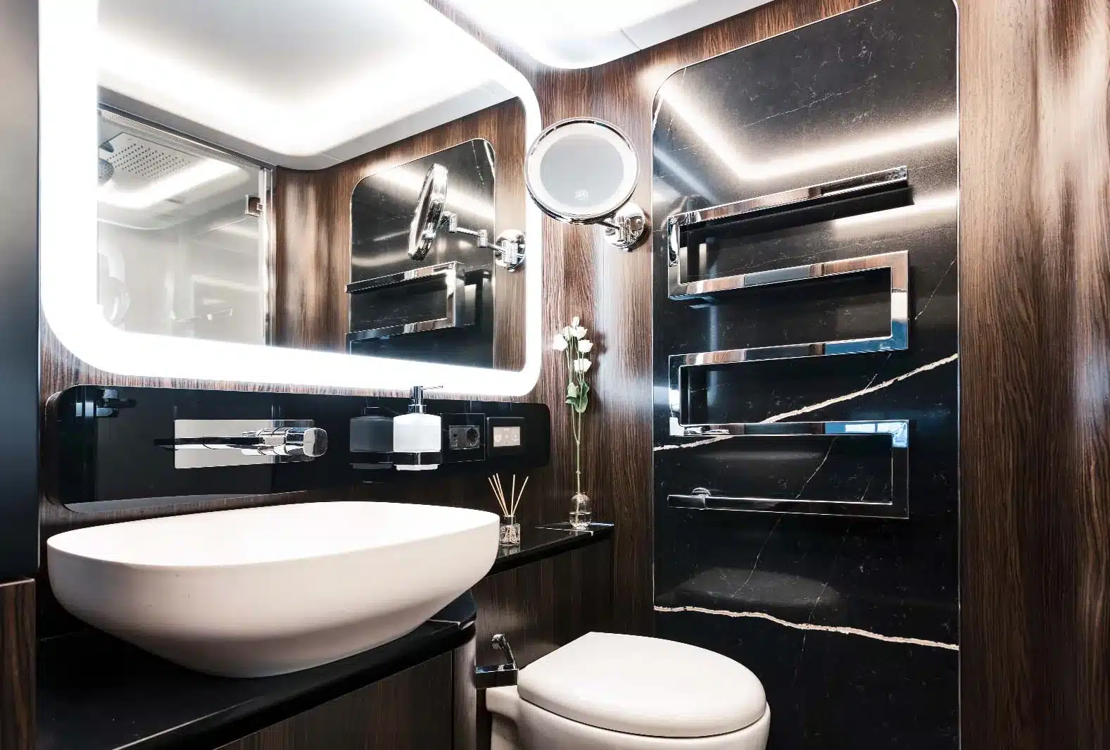 Badezimmer mit schwarzer Steinverkleidung, weißem Designer-Waschbecken und modernen Armaturen im Luxus-Reisemobil Dembell Smart-Garage.