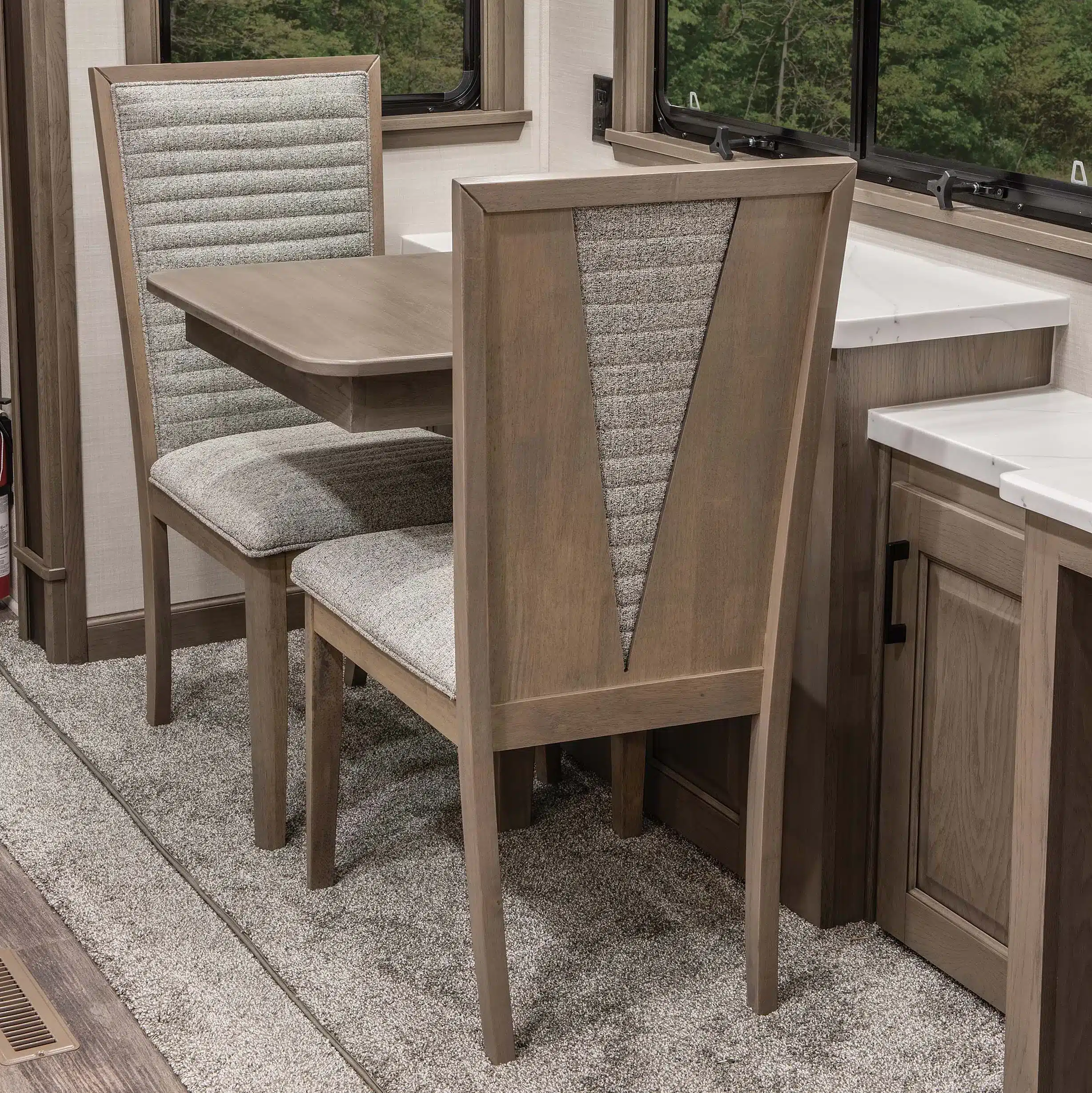 Essbereich mit zwei gepolsterten Stühlen und Holztisch im MS Houston Fifth Wheel Wohnwagen.