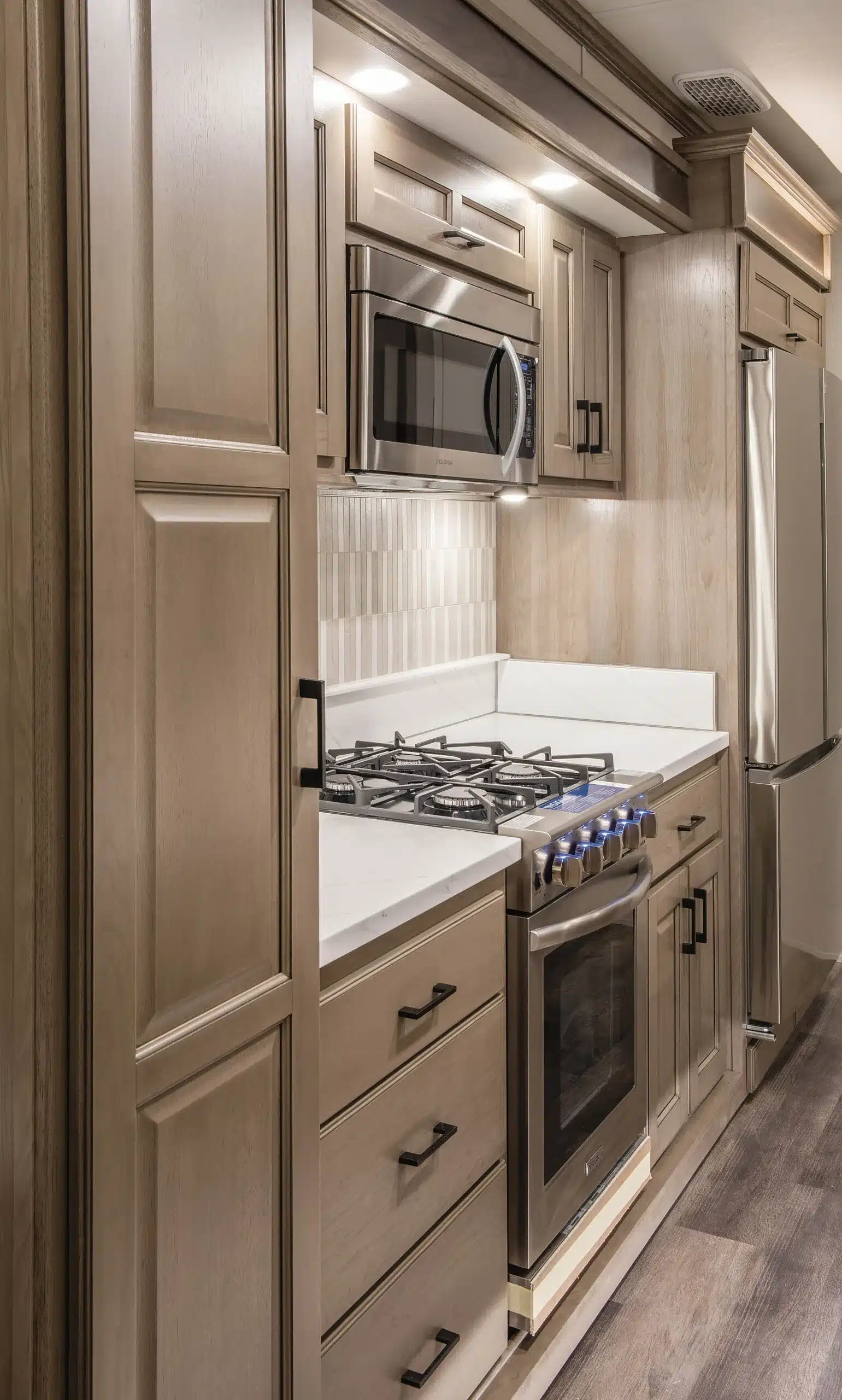 Moderne Einbauküche mit vierflammigem Gasherd, Backofen, Mikrowelle und großem Kühlschrank im DRV MS Houston Fifth Wheel.
