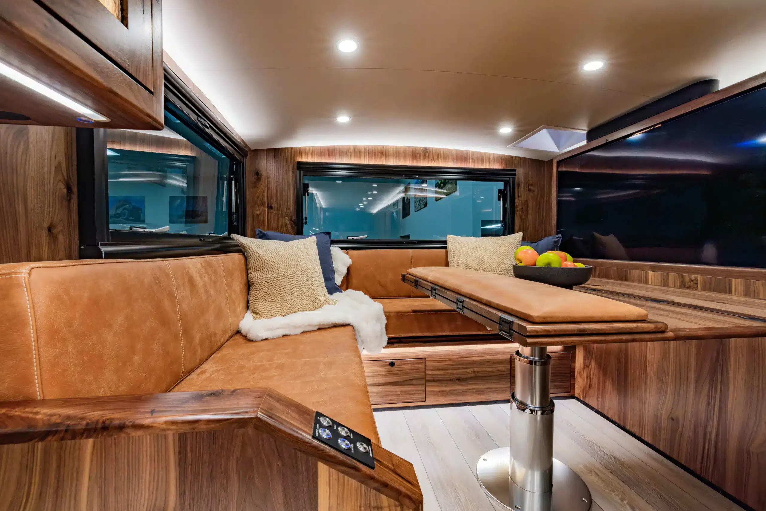 Innenansicht der Dinette mit Ledersitzfläche, Esstisch und großen Fenstern im EarthRoamer SX Explore