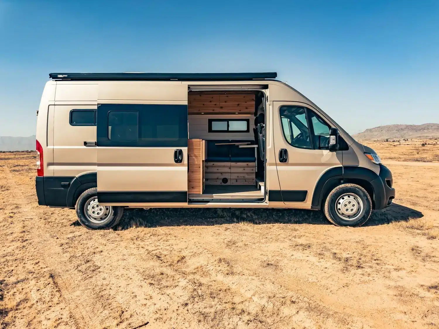 Goldfarbener Faith RAM Promaster Camper Van mit geöffneter Schiebetür und Blick auf den ausgebauten Innenraum, stehend in trockener Wüstenlandschaft