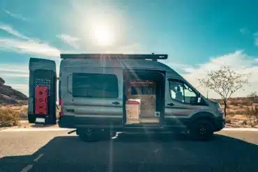 Ford Transit Trail Camper Van mit geöffnetem Heck und Blick auf den Innenausbau in sonniger Landschaft