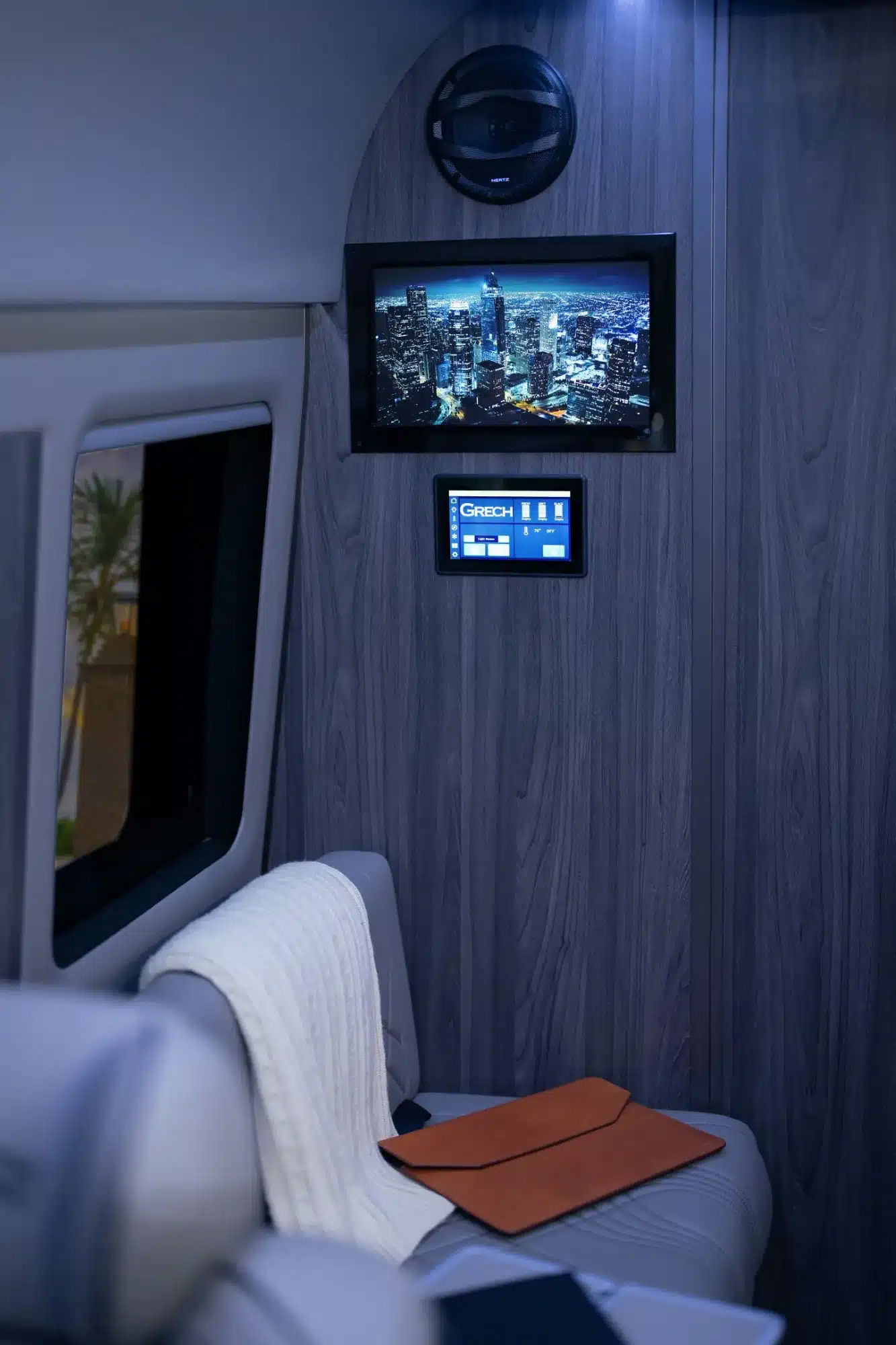 Entertainment-Display und zentrales Bedienpanel im Grech LUSSO Lounge Executive-Van, moderne Sitzfläche mit Decke und Dokumentenmappe.