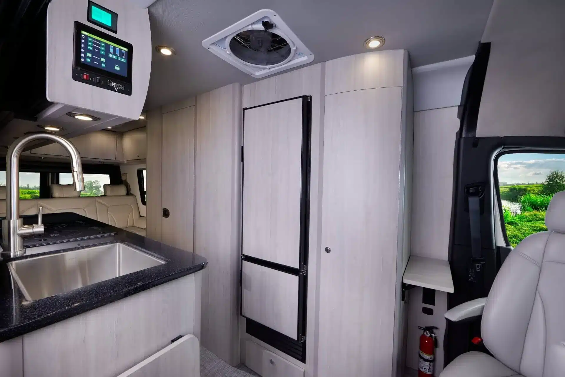 Innenansicht des Grech RV Strada-ion 2026 mit Küchenzeile, Induktionskochfeld, Lounge-Sitzen und modernen Einbauten