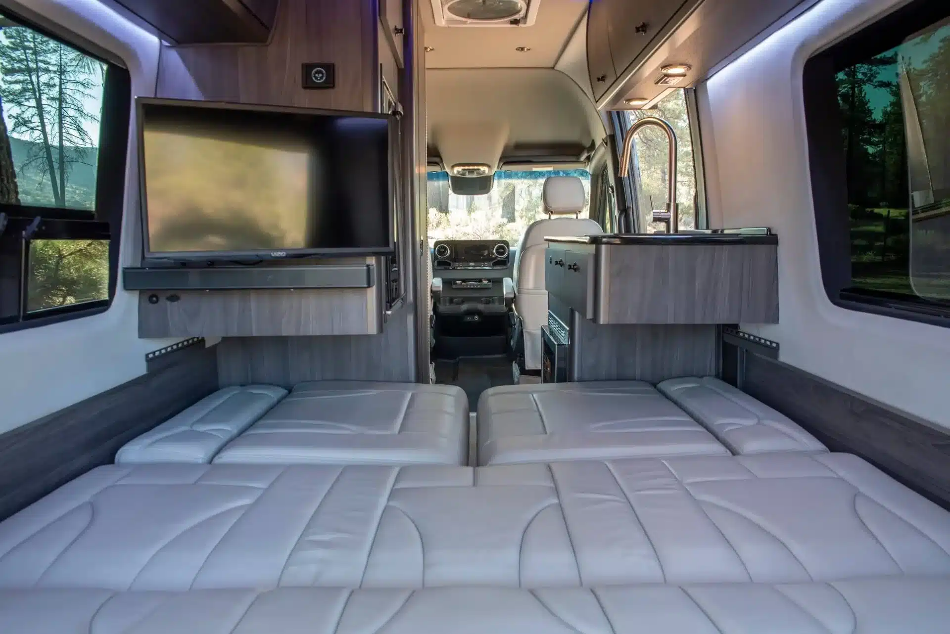 Wohnbereich des Grech Turismo-ion AWD 2026 mit elektrisch verstellbarer Sofa-Liegefläche, moderner Küche und LED-Beleuchtung