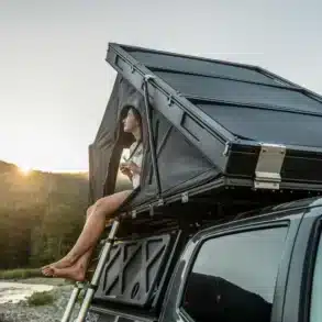 Offenes iKamper BDV Solo Dachzelt auf einem Auto mit einer Frau im Eingangsbereich
