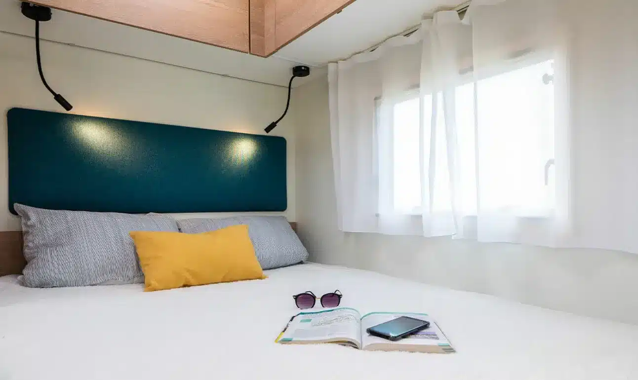 Innenansicht des Schlafbereichs im Joa Teilintegrierter 60F mit Kopfteil, Kissen und Fenster