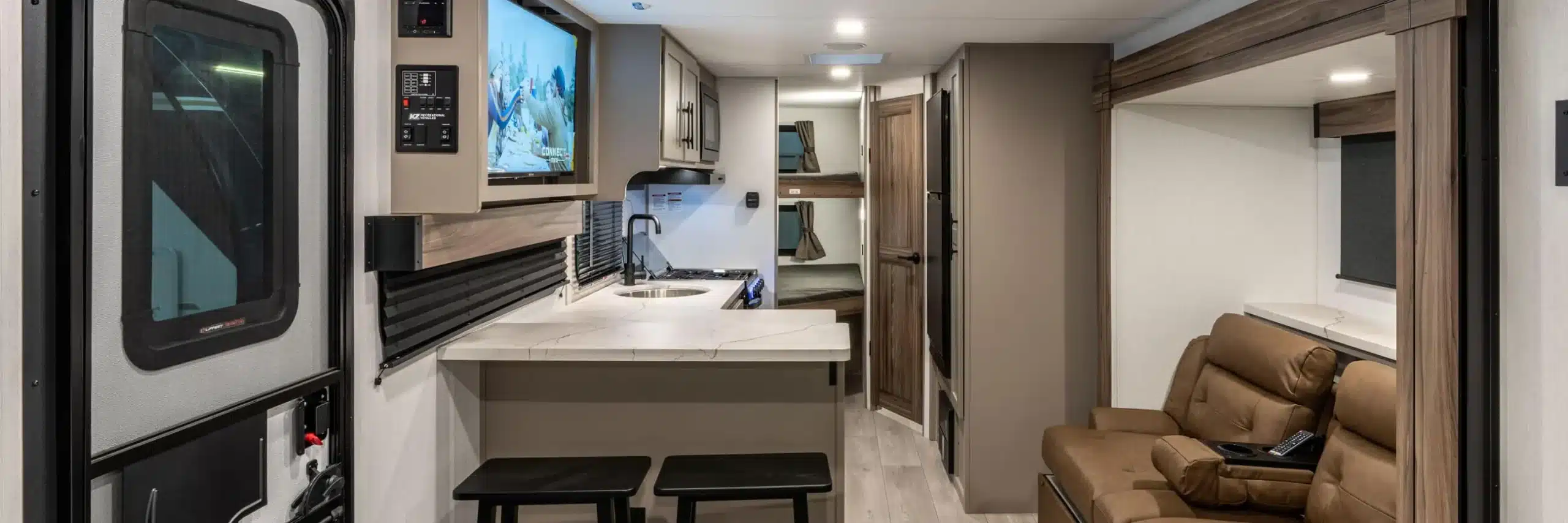 Blick in den Innenraum des KZ Connect Mini Wohnwagens mit Küchenzeile, TV und Sitzgelegenheiten