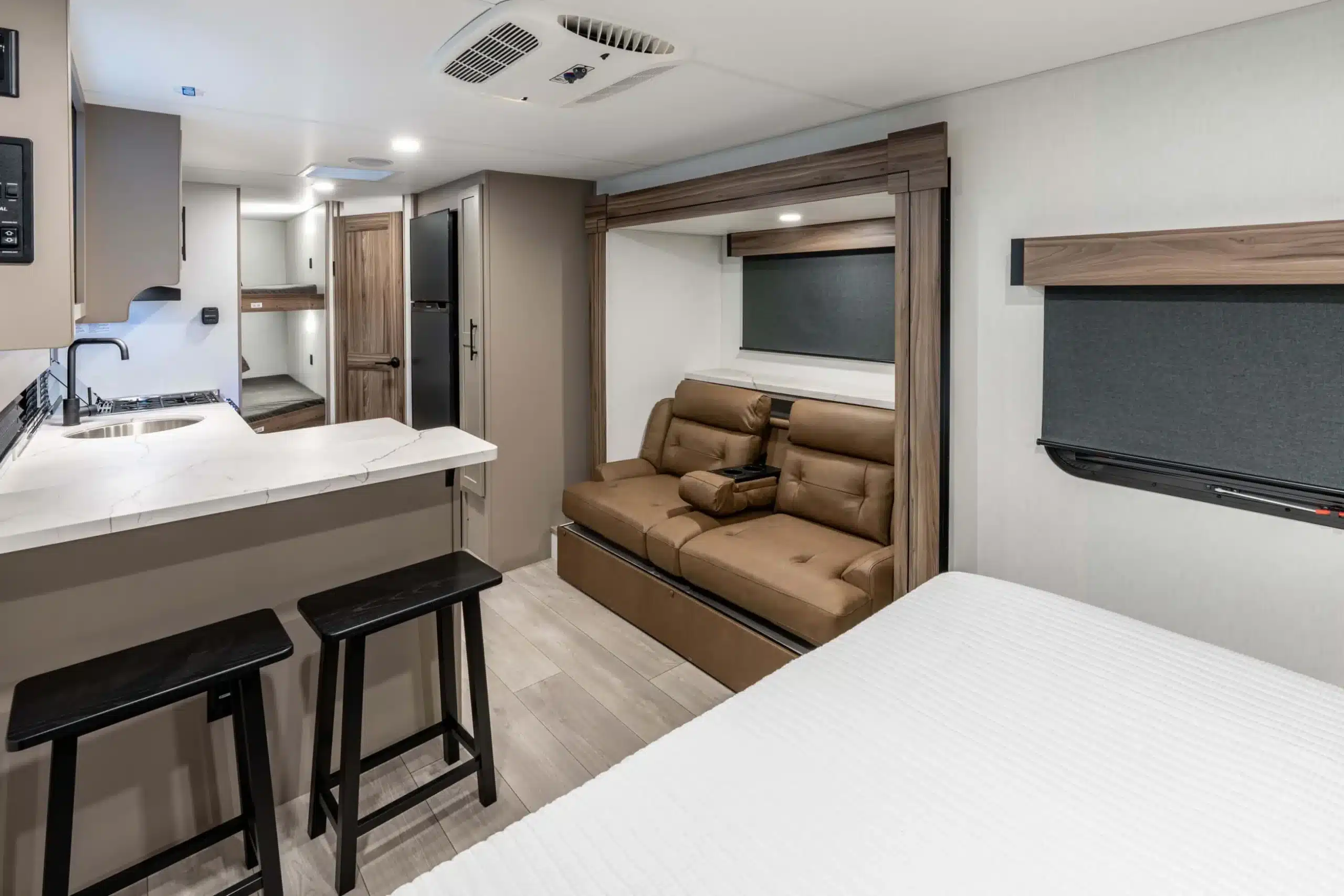 Moderner Innenraum eines KZ Connect Mini Wohnwagens mit Küche, Sitzbereich, zwei Stühlen und Schlafbereich